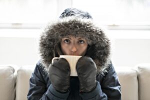 person-wearing-coat-and-mittens-indoors-and-sipping-hot-tea